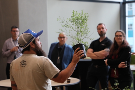 A man showing a native plant to a room of people